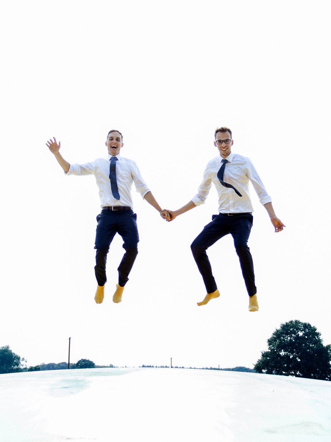 Kevin und Florian springen an ihrem Hochzeitstag Hand in Hand in die Luft